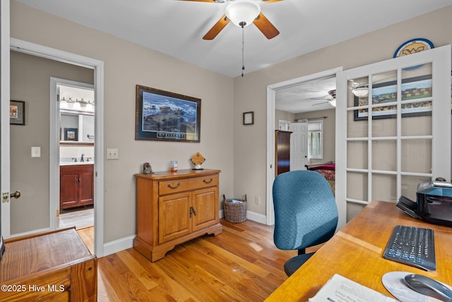 office area featuring a sink, light wood-style floors, baseboards, and a ceiling fan