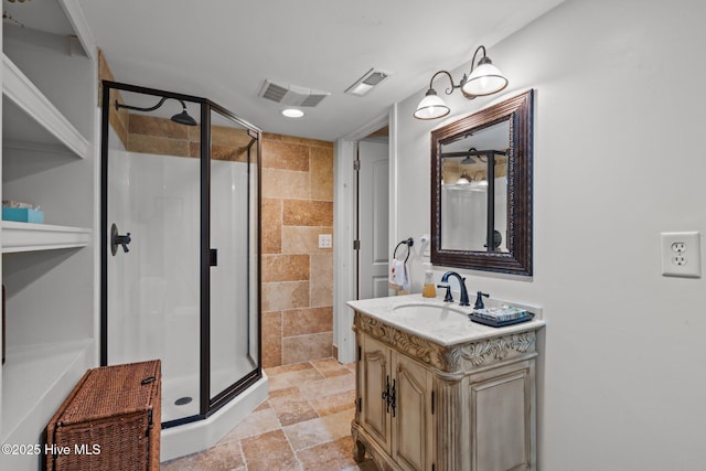 full bathroom with visible vents, a shower stall, stone tile floors, and vanity