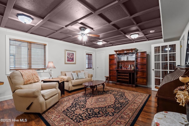 living room featuring coffered ceiling, ceiling fan, baseboards, and wood finished floors