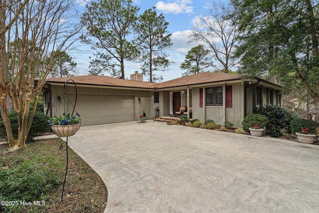 ranch-style home featuring a garage, driveway, and a chimney