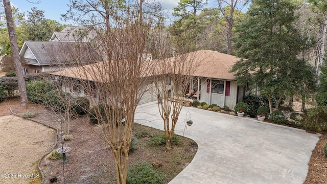 view of front facade with driveway, a garage, and roof with shingles