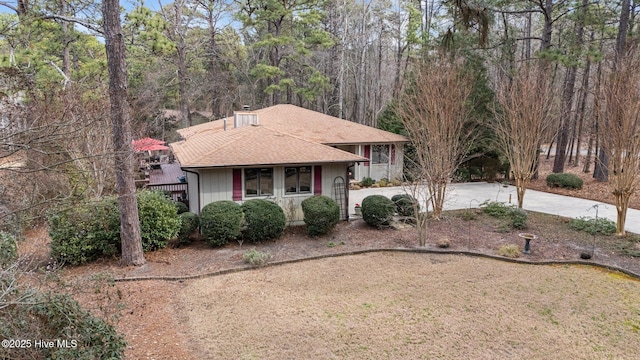 view of front of home featuring a shingled roof, driveway, and a chimney