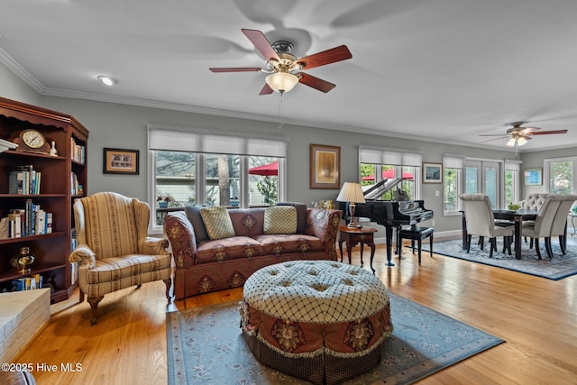 living room featuring a healthy amount of sunlight, baseboards, crown molding, and wood finished floors