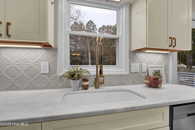 kitchen featuring stainless steel dishwasher, sink, and decorative backsplash