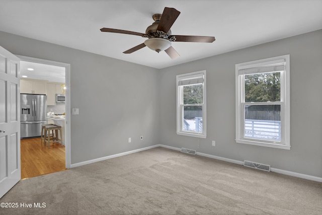 spare room with ceiling fan and light carpet