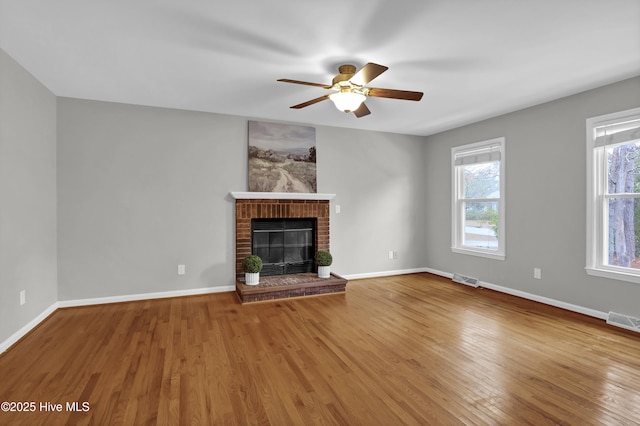 unfurnished living room featuring hardwood / wood-style flooring, ceiling fan, and a fireplace