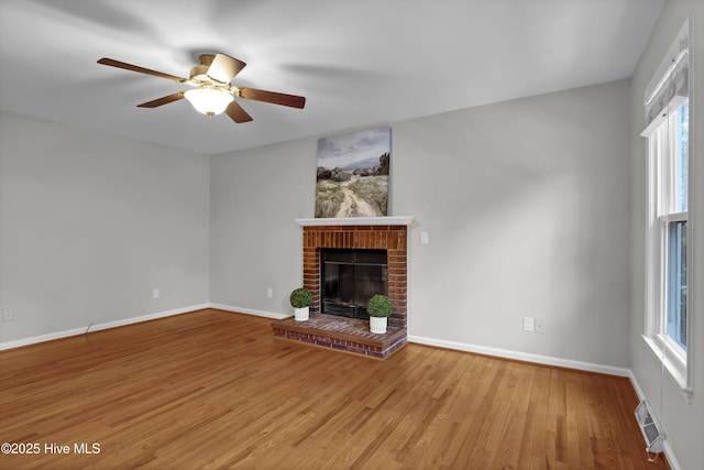 unfurnished living room with ceiling fan, a healthy amount of sunlight, a fireplace, and light wood-type flooring