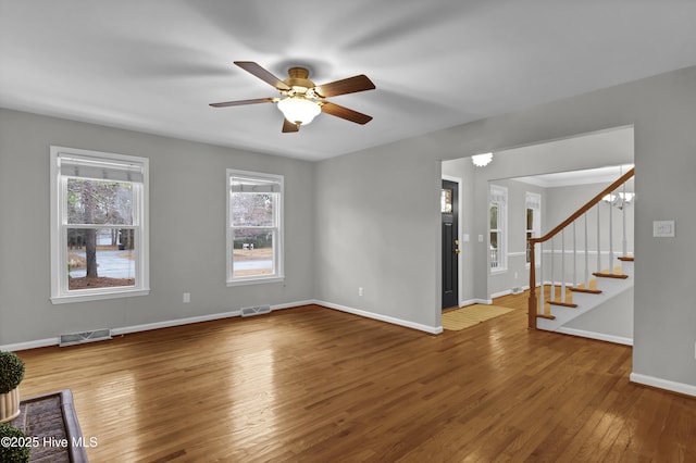 unfurnished living room featuring ceiling fan with notable chandelier and hardwood / wood-style floors