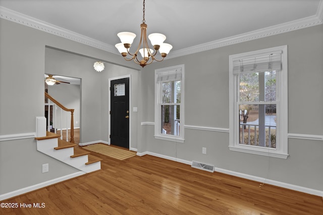 foyer entrance with ceiling fan with notable chandelier, ornamental molding, and hardwood / wood-style floors