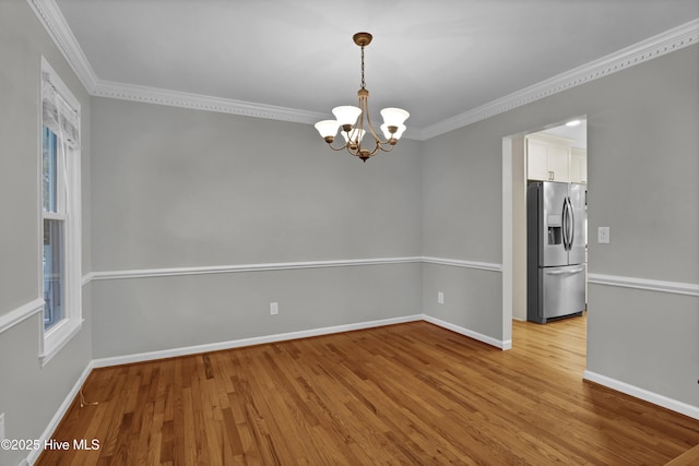 spare room featuring ornamental molding, light hardwood / wood-style flooring, and a notable chandelier