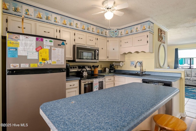 kitchen featuring stainless steel appliances, sink, a textured ceiling, and cream cabinetry