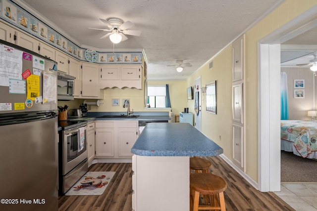 kitchen featuring sink, a breakfast bar, appliances with stainless steel finishes, a textured ceiling, and a kitchen island