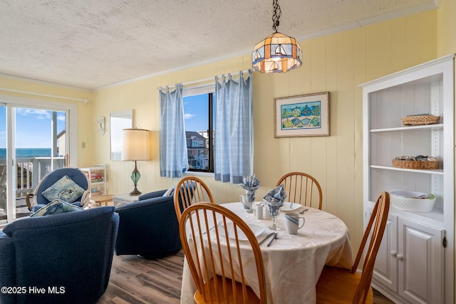 dining space featuring hardwood / wood-style flooring, a healthy amount of sunlight, crown molding, and a textured ceiling