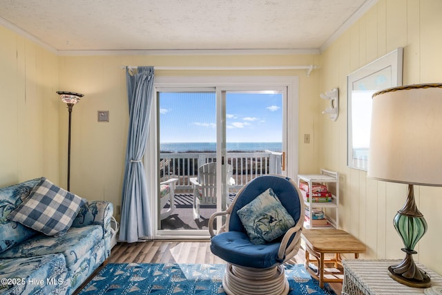 sitting room featuring hardwood / wood-style flooring, crown molding, a water view, and a textured ceiling