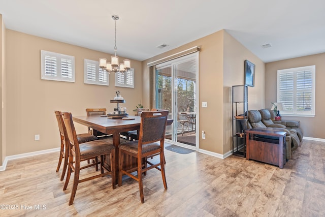 dining area featuring light wood-type flooring, a wealth of natural light, and a chandelier