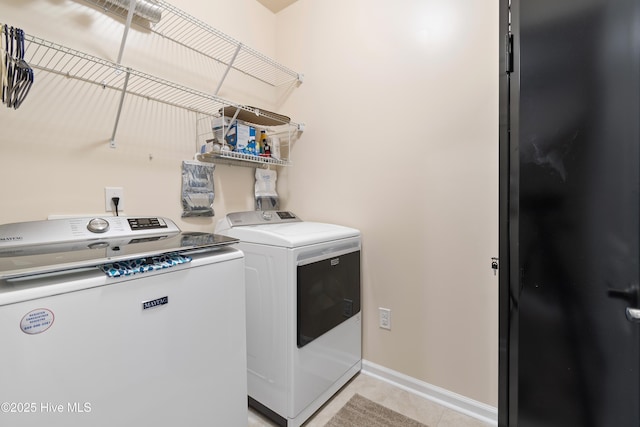 clothes washing area featuring light tile patterned floors and washer and dryer