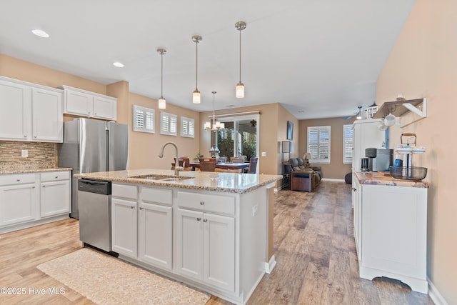 kitchen with appliances with stainless steel finishes, decorative backsplash, pendant lighting, white cabinets, and sink