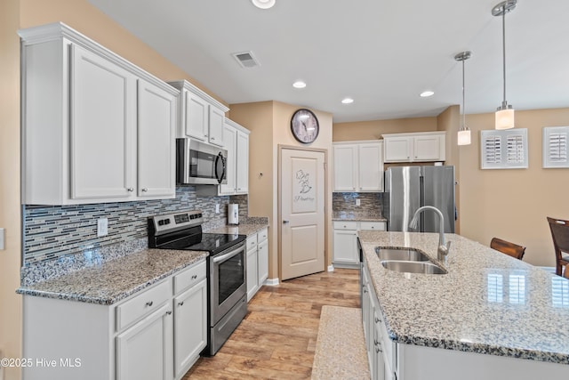 kitchen featuring decorative light fixtures, white cabinets, appliances with stainless steel finishes, and sink