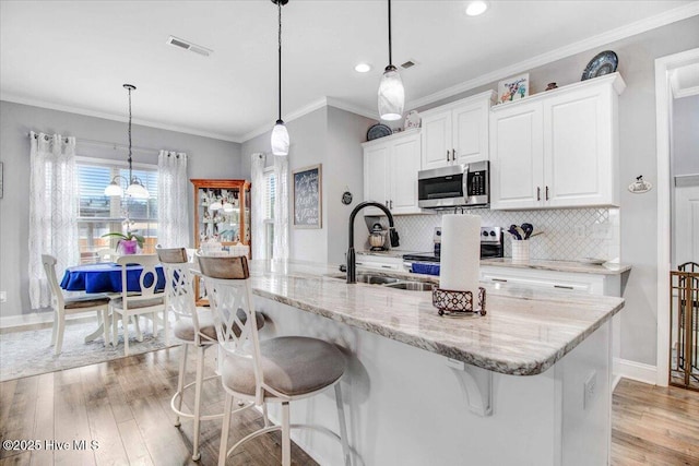 kitchen with pendant lighting, white cabinetry, a kitchen breakfast bar, an island with sink, and stainless steel appliances