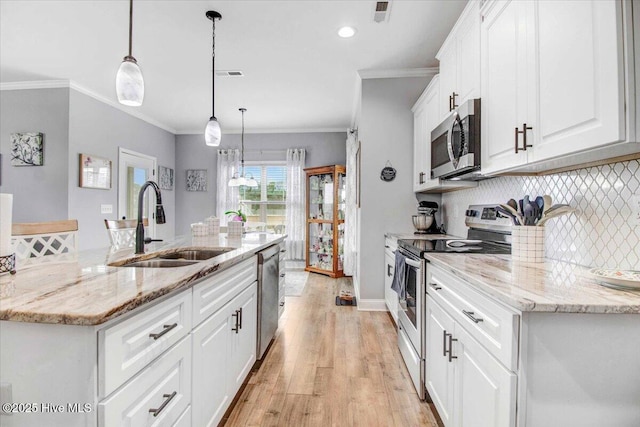 kitchen featuring decorative light fixtures, backsplash, a kitchen island with sink, stainless steel appliances, and white cabinets