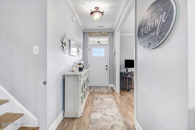 foyer with crown molding and light hardwood / wood-style floors