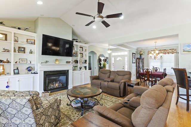 living room with ceiling fan with notable chandelier, lofted ceiling, and light wood-type flooring