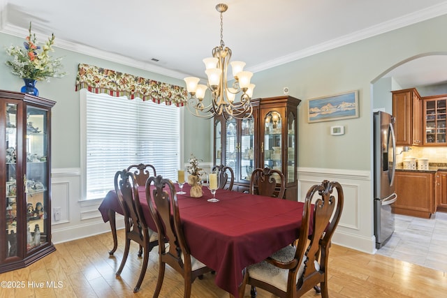 dining space featuring ornamental molding, light hardwood / wood-style flooring, and a notable chandelier