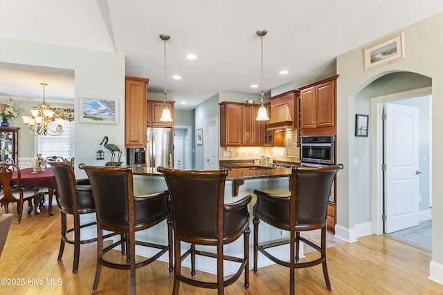 kitchen with decorative light fixtures, dark stone countertops, a breakfast bar, an inviting chandelier, and stainless steel appliances