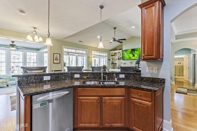 kitchen featuring pendant lighting, dark stone countertops, sink, stainless steel dishwasher, and light hardwood / wood-style flooring