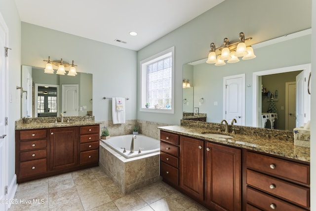 bathroom with a healthy amount of sunlight, vanity, washer and dryer, and tiled tub