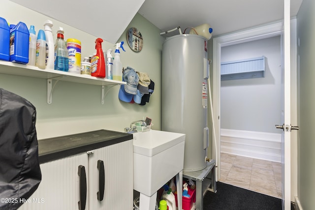 laundry room featuring water heater, sink, and light tile patterned flooring