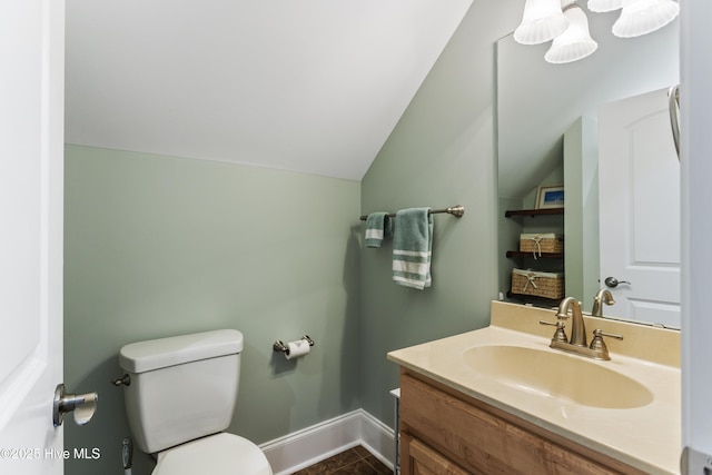 bathroom with tile patterned floors, toilet, vanity, and lofted ceiling