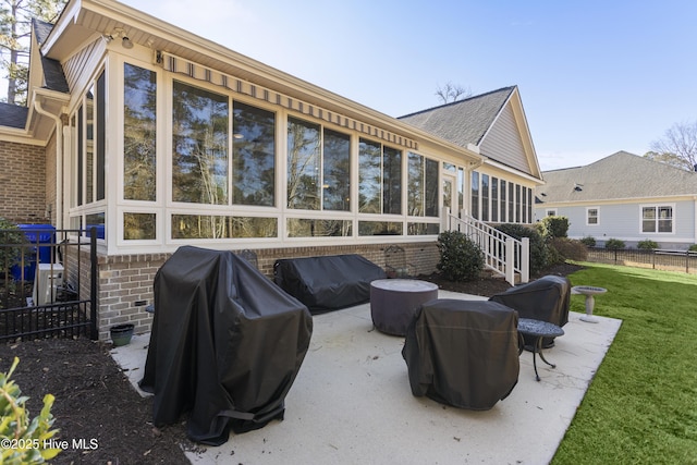 rear view of house featuring a sunroom, a lawn, and a patio