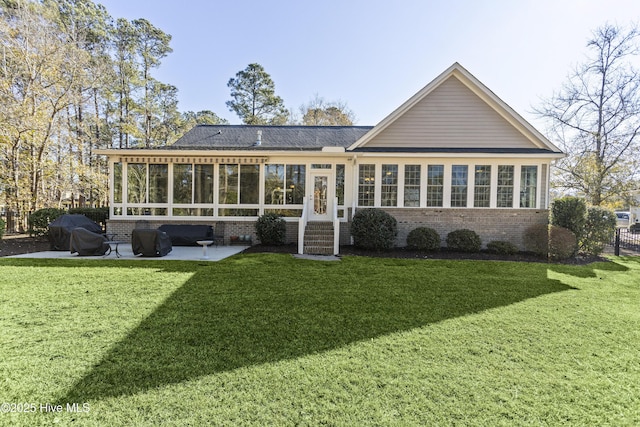 rear view of house with a sunroom, a yard, and a patio