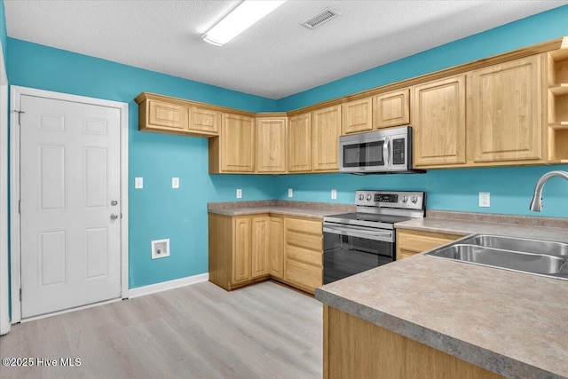 kitchen with stainless steel appliances, sink, a textured ceiling, and light hardwood / wood-style flooring