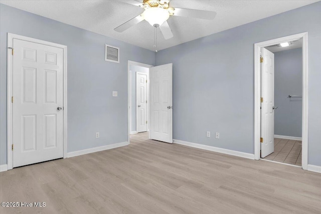 unfurnished bedroom with ceiling fan, light hardwood / wood-style flooring, and a textured ceiling