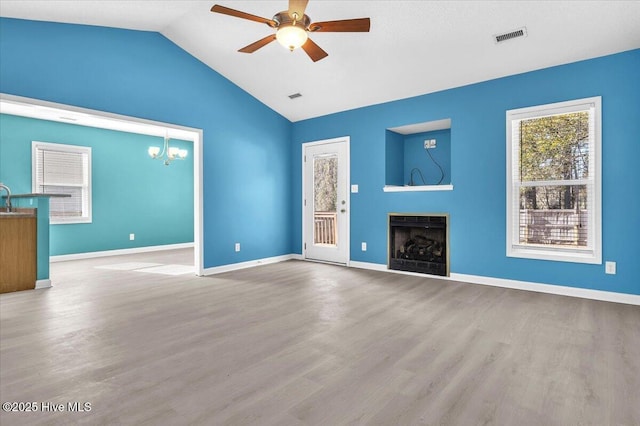 unfurnished living room featuring ceiling fan with notable chandelier, wood-type flooring, sink, and vaulted ceiling