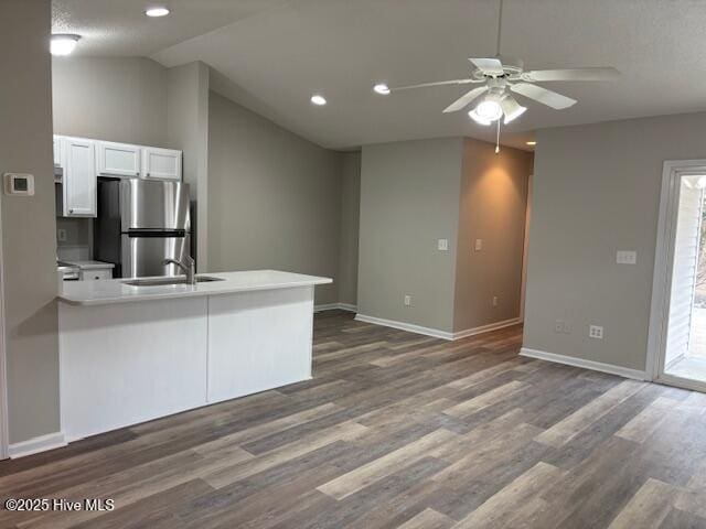 kitchen featuring white cabinetry, kitchen peninsula, ceiling fan, stainless steel refrigerator, and sink