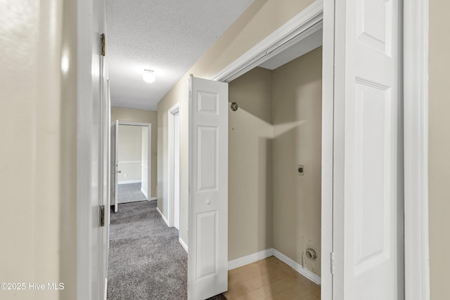 corridor featuring a textured ceiling and carpet flooring