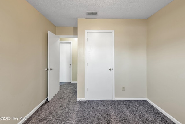 unfurnished bedroom featuring a textured ceiling and dark colored carpet