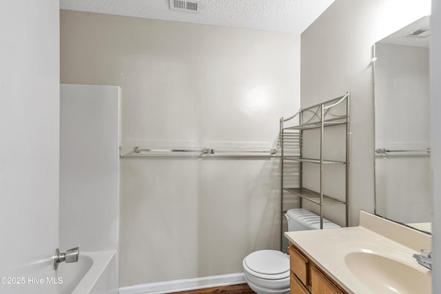 full bathroom featuring toilet, vanity, a textured ceiling, and washtub / shower combination