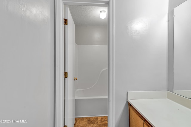 bathroom featuring a shower, a textured ceiling, and vanity