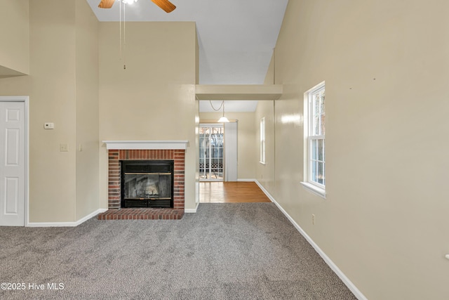 unfurnished living room with ceiling fan, carpet, high vaulted ceiling, and a fireplace