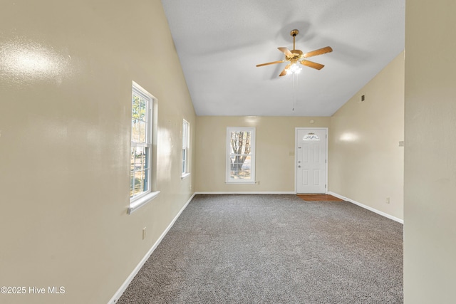 empty room featuring ceiling fan, a wealth of natural light, vaulted ceiling, and carpet flooring