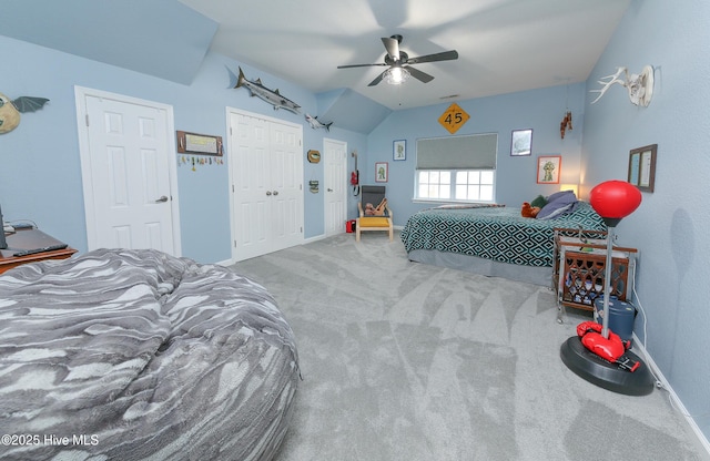 bedroom featuring ceiling fan, light colored carpet, and two closets