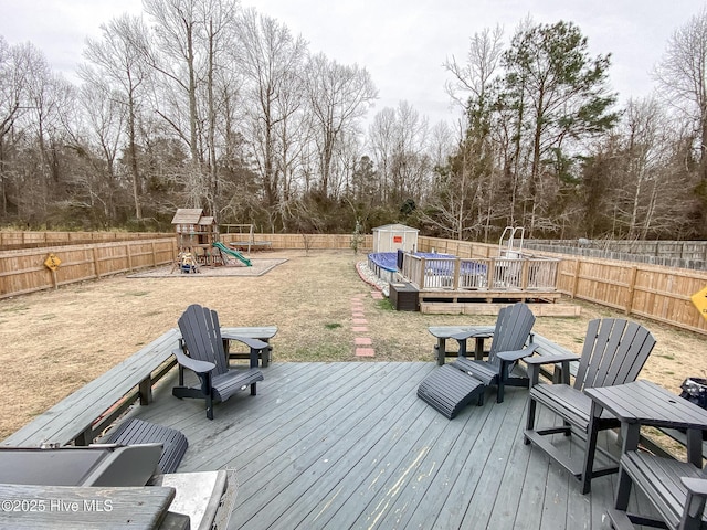 wooden deck featuring a playground and a shed