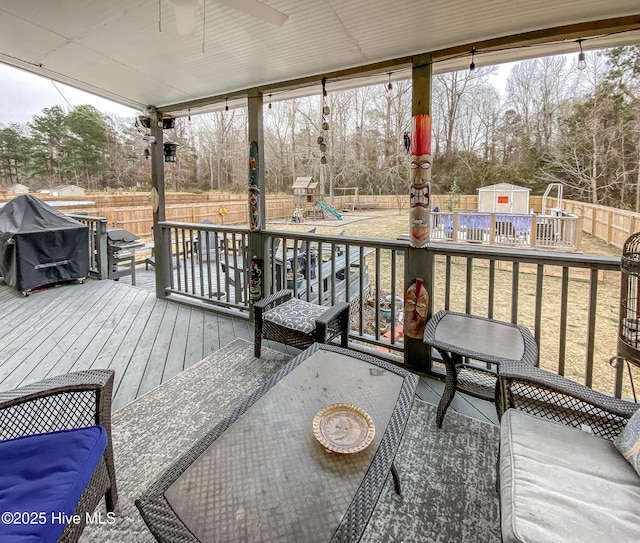 deck featuring ceiling fan, a playground, and a grill