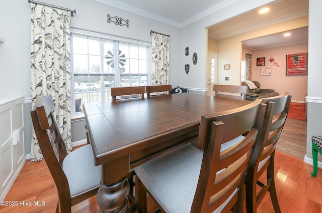 dining room featuring light wood-type flooring and crown molding