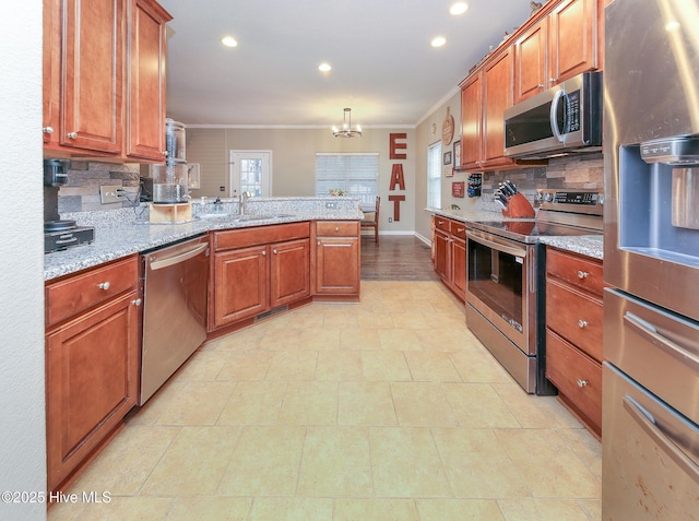 kitchen with crown molding, hanging light fixtures, appliances with stainless steel finishes, sink, and light stone countertops