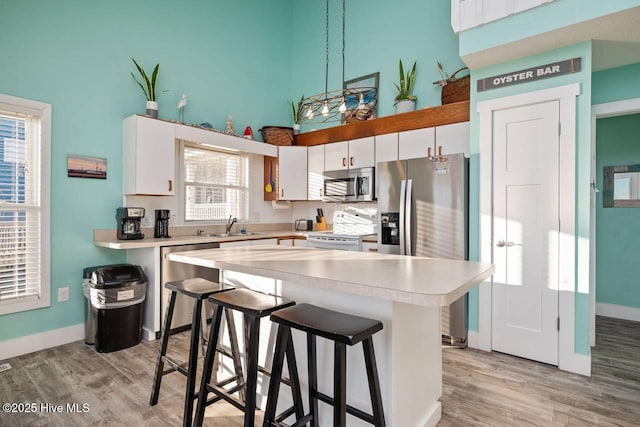 kitchen featuring appliances with stainless steel finishes, plenty of natural light, white cabinets, and a kitchen breakfast bar